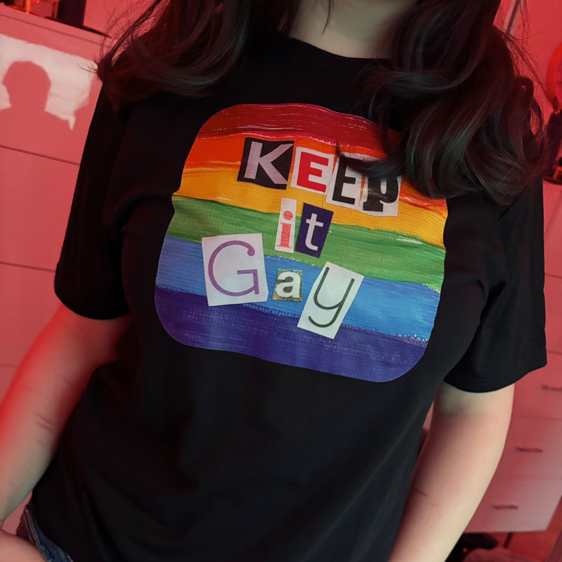 Person wearing a black t-shirt with a rainbow-colored graphic and text 'KEEP it Gay' on a red background.
