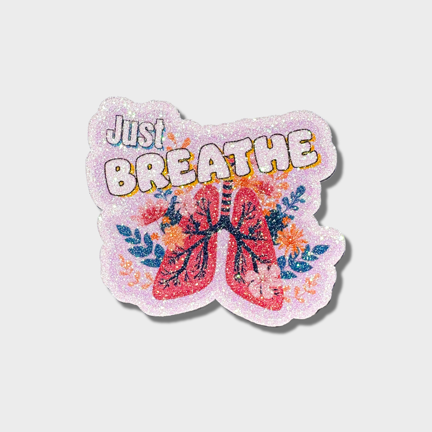Glitter sticker with 'Just Breathe' text and lungs design on a light purple background