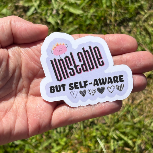 Sticker  that says "unstable but self aware" with a grassy background