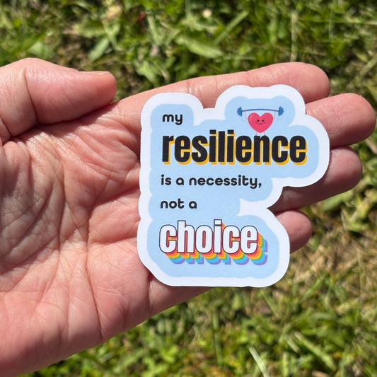Hand holding a sticker with text that says my resilience is a necessity, not a choice, against a grassy background