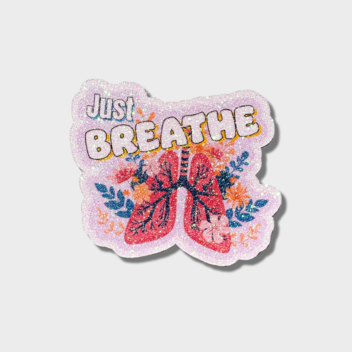 Glitter sticker with 'Just Breathe' text and lungs design on a light purple background