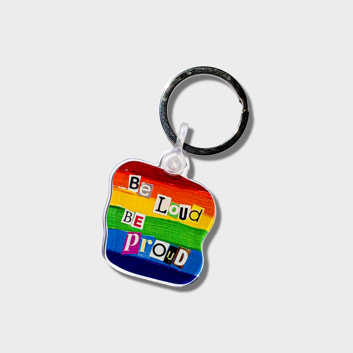 Keychain with rainbow design and 'Be Loud Be Proud' text on a white background