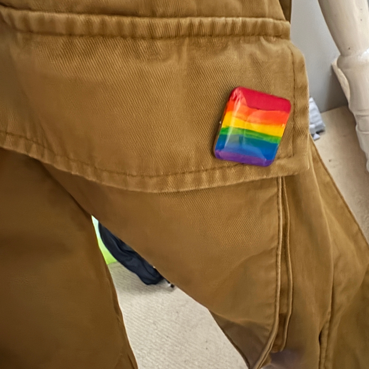 Rainbow flag pin on a brown jacket