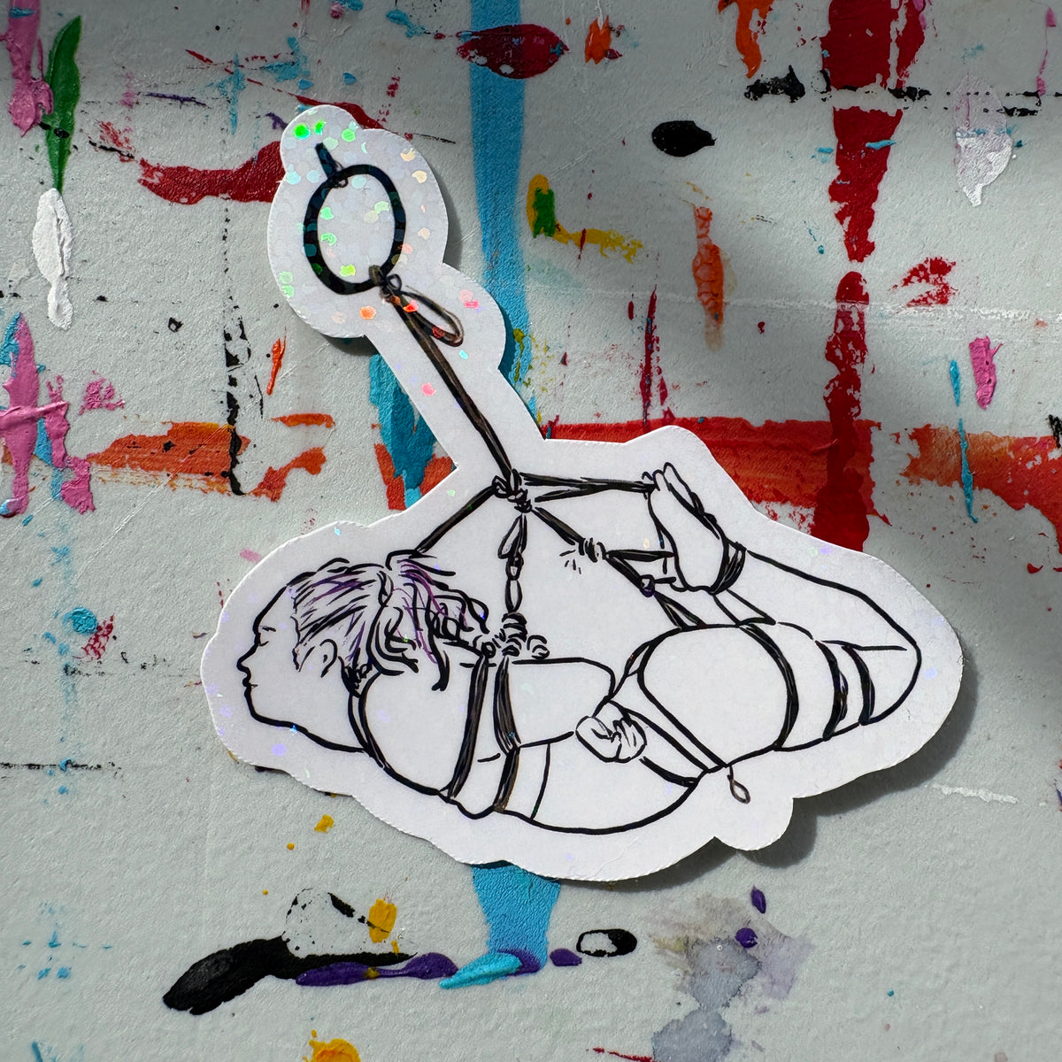 Sticker of a person in a hogtie rope suspension on a colorful, textured background