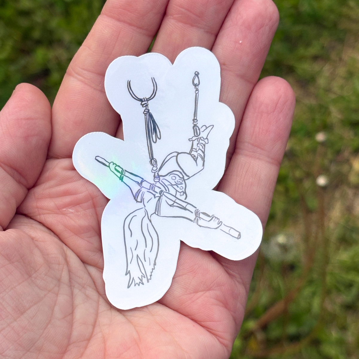 White sticker of a person in a face down rope suspension with her arms tied to bamboo